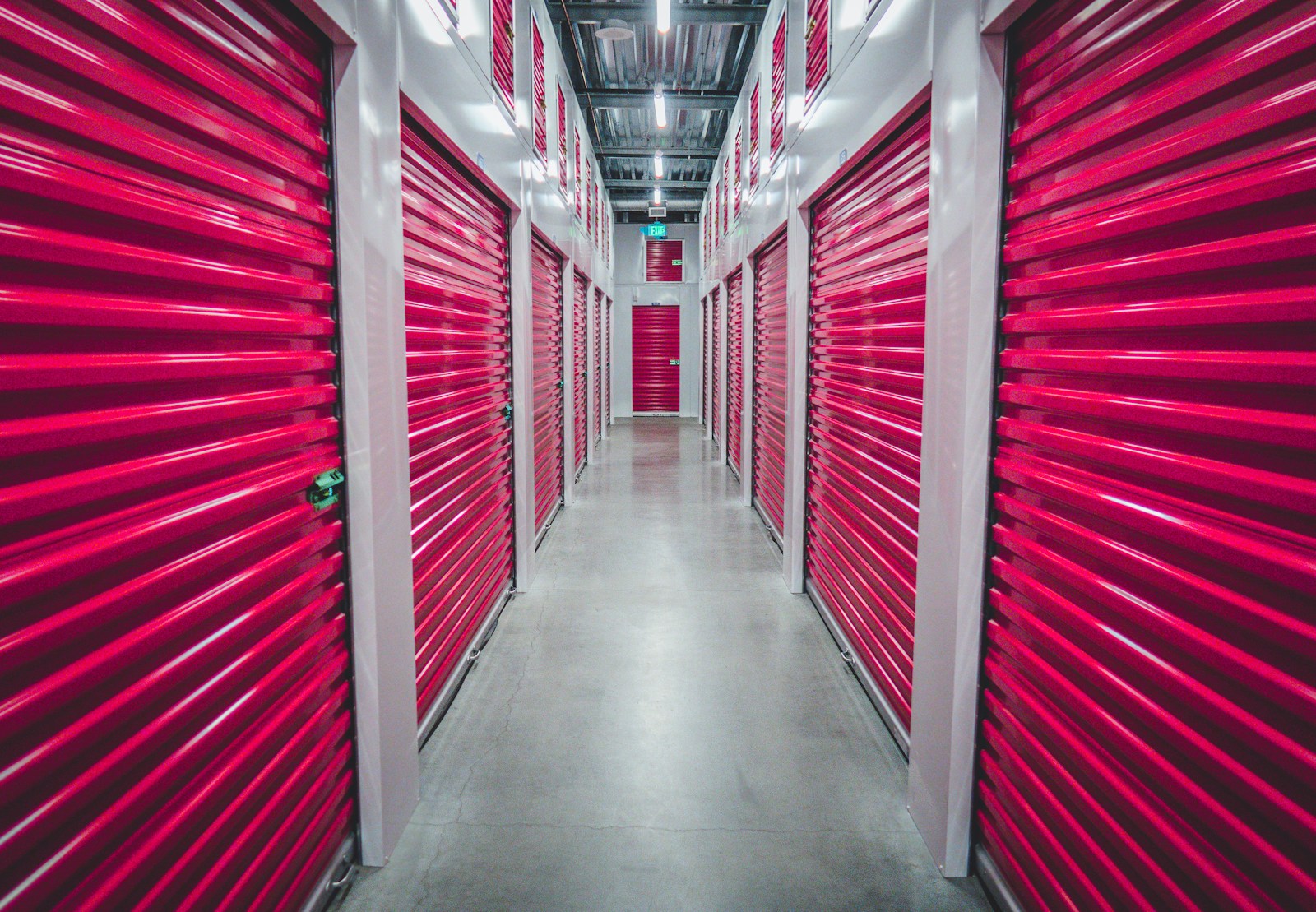 A corridor of closed storage units, roller doors shut on both sides.
